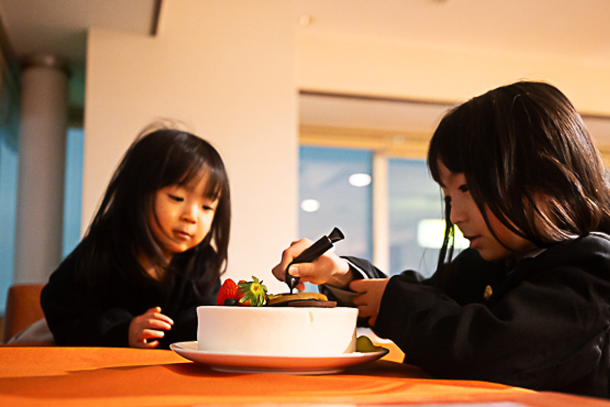ケーキ屋さん体験、チョコペンで絵を描く姉妹